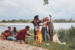 Enjoying the nature. Group of people have picnic on the beach. Friends have fun at weekend time photo