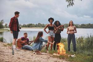 Talking with each other. Group of people have picnic on the beach. Friends have fun at weekend time photo