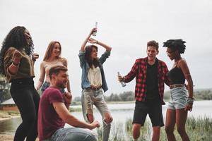 no seas tímido y baila. grupo de personas hacen picnic en la playa. los amigos se divierten el fin de semana foto