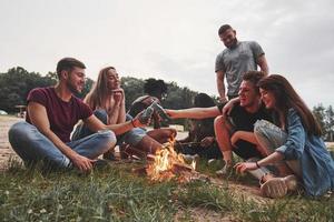 acampar en la playa. grupo de personas tienen picnic. los amigos se divierten el fin de semana foto