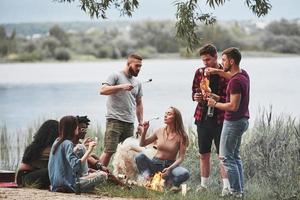 Under the tree. Group of people have picnic on the beach. Friends have fun at weekend time photo