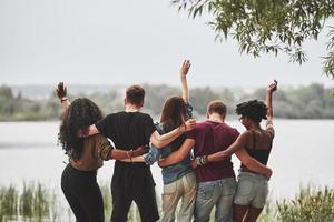 Looking at the lake. People have party outside. Multi ethnic friends have meeting at weekend time photo