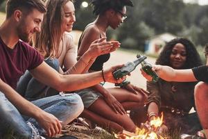 no hay fiestas sin alcohol para ellos. grupo de personas hacen picnic en la playa. los amigos se divierten el fin de semana foto