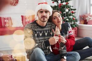 In the great room with awesome interior. Two people sits on the floor and celebrate new year photo