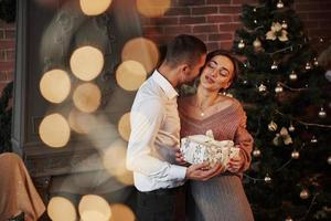 Conception of holidays. Christmas gift for the woman. Gentleman in classic suit gives his wife the present photo