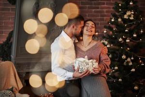 Girl is smiling. Christmas gift for the woman. Gentleman in classic suit gives his wife the present photo