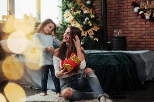 Family happiness. Mother and daughter sits in holiday decorated room and holds gift box photo