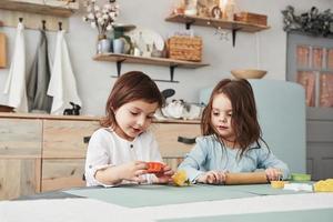 Just having free time. Two kids playing with yellow and orange toys in the white kitchen photo