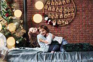 Children finally met each other. Little girls having fun on the bed with holiday interior at the background photo