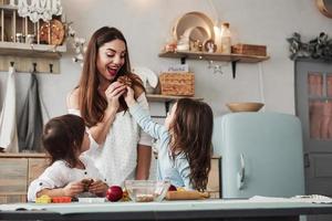 Cute girl decide to share. Mom is happy. Young beautiful woman give the cookies while they sitting near the table with toys photo