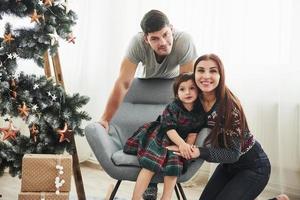 Portrait of the happy family on the new year celebration. Girl sits on the chair photo