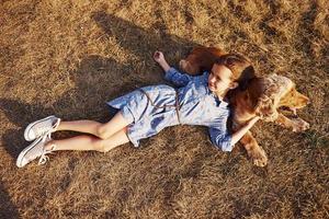 vista superior. tendido en el césped. una linda niña da un paseo con su perro al aire libre en un día soleado
