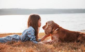 Side view. Cute little girl have a walk with her dog outdoors at sunny day photo