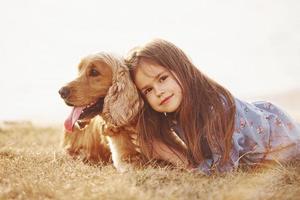 Feeling happy and embracing the pet. Cute little girl have a walk with her dog outdoors at sunny day photo