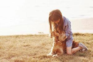Playing with pet. Cute little girl have a walk with her dog outdoors at sunny day photo