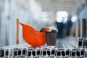 Bread is on the cup with drink. Orange hard hat on objects in the factory. No people. Conception of lunch break photo