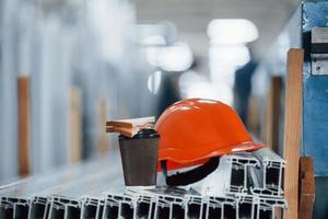 Bread is on the cup with drink. Orange hard hat on objects in the factory. No people. Conception of lunch break photo