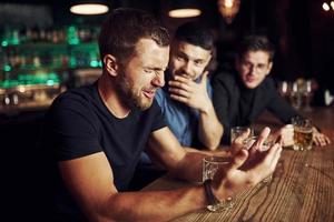 Three male friends in the bar. Supporting sad friend. Unity of people. With beer on the table photo