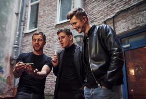 Three male friends stands outside the bar. Having conversation. In nice clothes photo