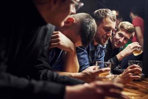 Guy feels awful. Friends resting in the pub with alcohol in hands. Having conversation photo