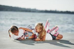 dos niñas pequeñas con patines al aire libre cerca del lago al fondo foto