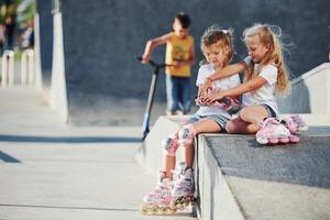 en la rampa para los deportes extremos. dos niñas pequeñas con patines al aire libre se divierten foto