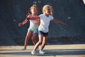 Having fun with bubbles. Leisure activities. Two little girls having fun in the park photo