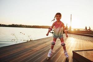 Happy cute kid riding on her roller skates. Summertime leisure and weekends photo