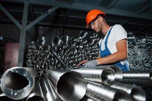 la computadora portátil ayuda a buscar información. hombre en uniforme trabaja en la producción. tecnología industrial moderna foto