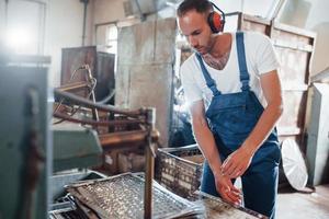 Preparing some materials to manufacturing. Man in uniform works on the production. Industrial modern technology photo