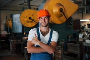 chico positivo. retrato de ingeniero en fábrica metalúrgica en casco protector foto