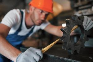 Measuring the detail. Man in uniform works on the production. Industrial modern technology photo