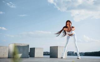 Shot of sportive woman doing fitness exercises near the lake at daytime photo