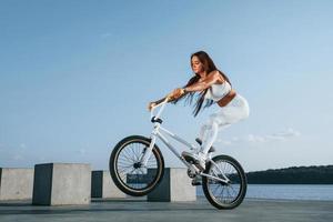 jinete femenino está en la bicicleta durante el día cerca del lago. mujer fitness en ropa deportiva foto