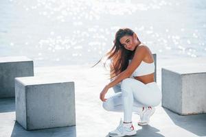 mujer fitness descansando cerca del lago durante el día. hermosa luz del sol foto