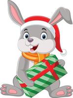 Cartoon rabbit wearing scarf and hat holding gift box vector