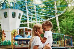 Loving each other. Cheerful little girl her mother have a good time in the park together near attractions photo