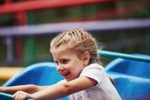 retrato de una niña feliz diviértete en una montaña rusa en el parque durante el día foto