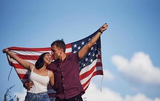 siente libertad. hermosa pareja con bandera americana pasar un buen rato al aire libre en el campo foto