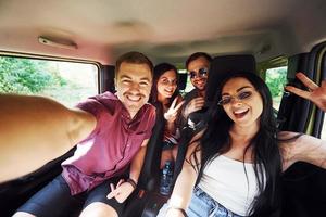 Young and cheerful people making a selfie inside a car. Having weekend photo