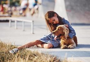 Embracing the pet. Cute little girl have a walk with her dog outdoors at sunny day photo