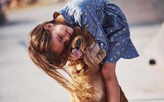 In love with her pet. Cute little girl have a walk with her dog outdoors at sunny day photo