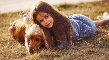 Feeling happy and embracing the pet. Cute little girl have a walk with her dog outdoors at sunny day photo