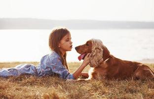 Side view. Cute little girl have a walk with her dog outdoors at sunny day photo