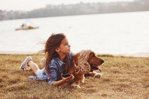 Swimming trasport behing on the lake. Cute little girl have a walk with her dog outdoors at sunny day photo