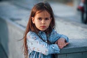 niñita vestida de azul posando para una cámara en la ciudad cuando se apoya en la rampa foto
