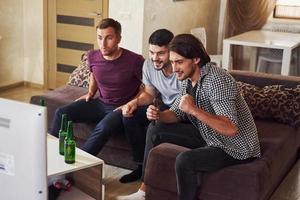 Excited three friends watching soccer on TV at home together photo