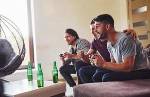 Group of friends have fun playing console game indoors at living room photo