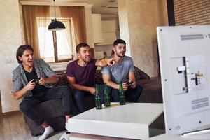 Group of friends have fun playing console game indoors at living room photo