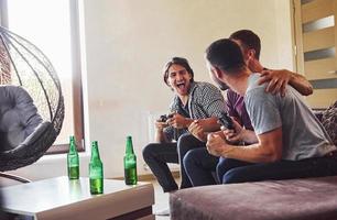 Group of friends have fun playing console game indoors at living room photo